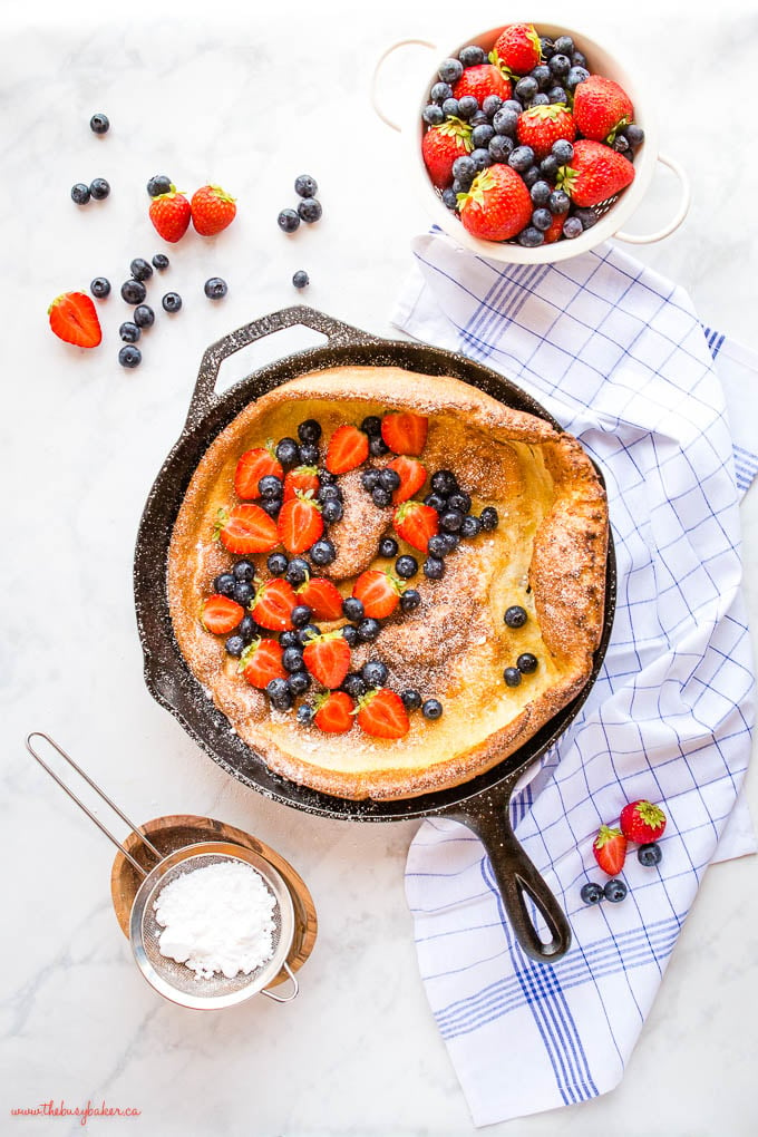 overhead image: dutch baby pancake with fresh berries and powdered sugar in a skillet