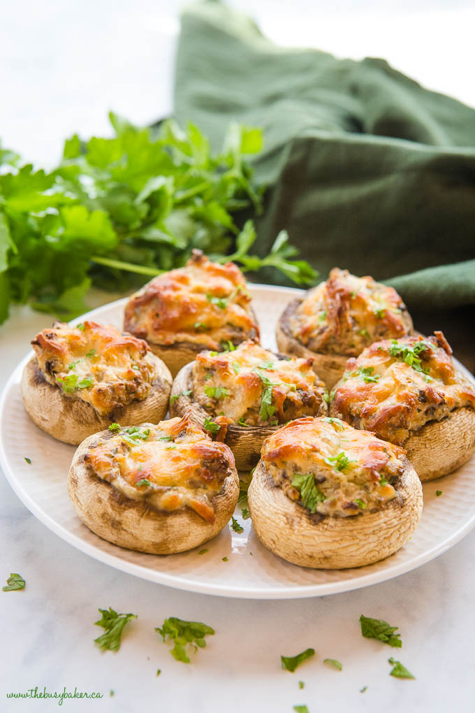 Stuffed Mushrooms on a white plate with cheese and fresh parsley