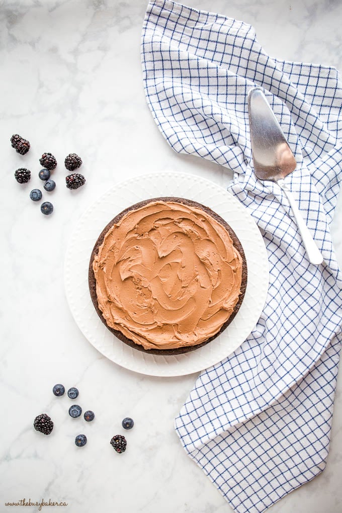 overhead image: chocolate cake on white plate with chocolate frosting and fresh blueberries and blackberries