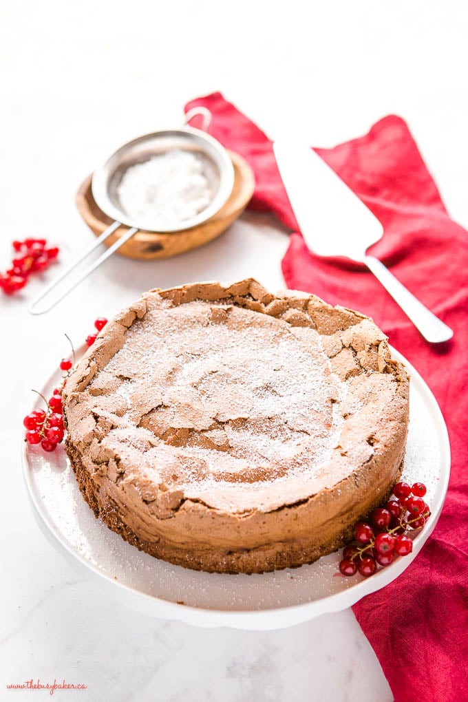 flourless chocolate cake on cake stand with red currants