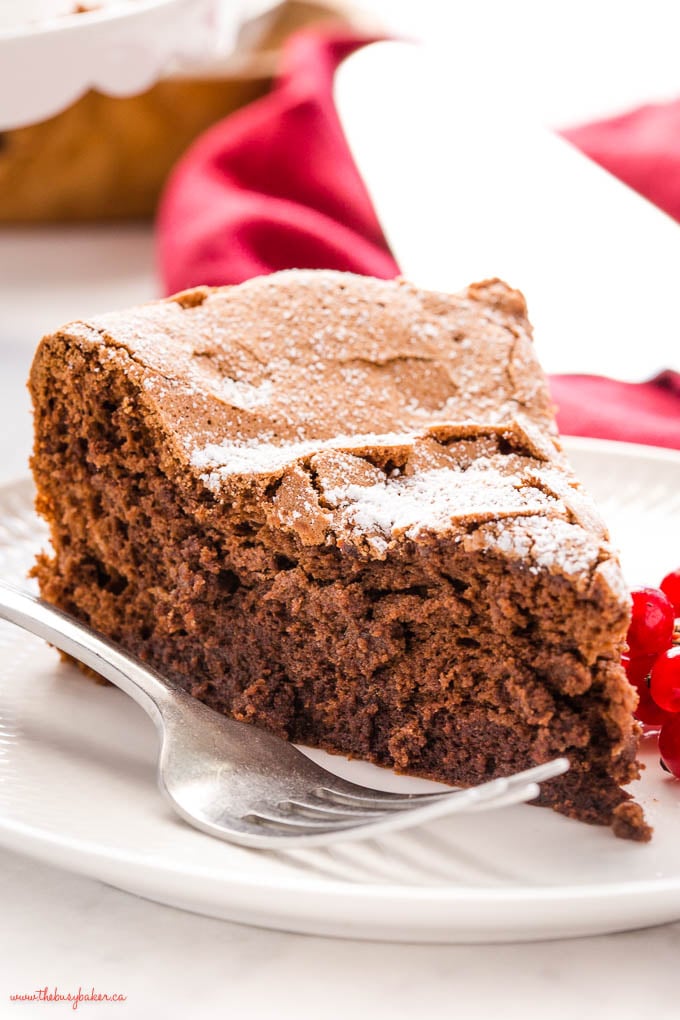 slice of fudgy flourless chocolate cake on white plate with a fork