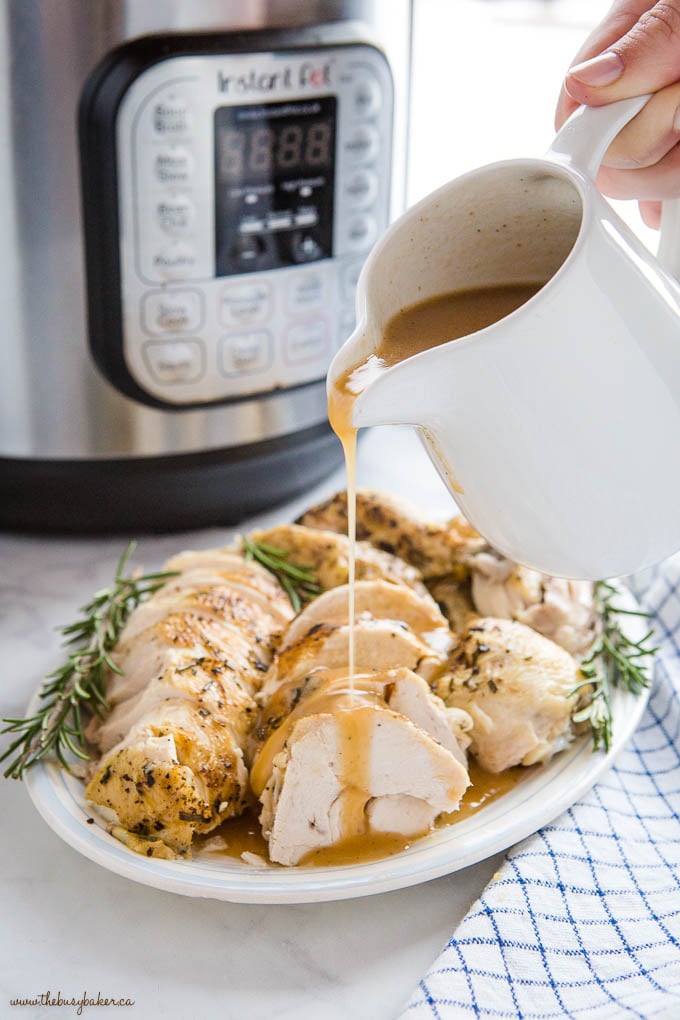 woman's hand pouring gravy over roast chicken with the Instant Pot in the background