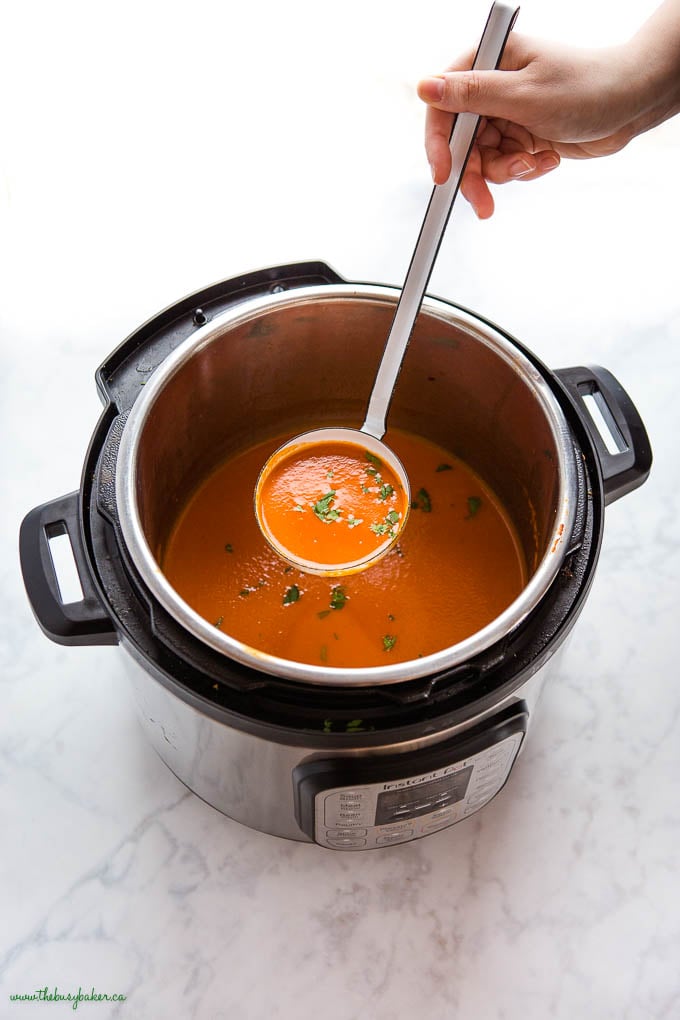 hand holding ladle of Instant Pot Tomato Soup