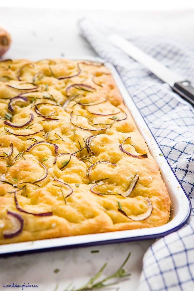 closeup image: focaccia bread in white pan with blue rim