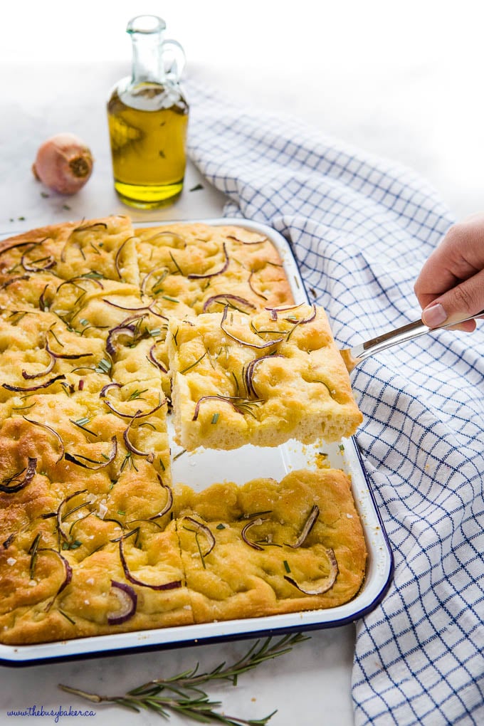 hand lifting a slice of rosemary focaccia bread