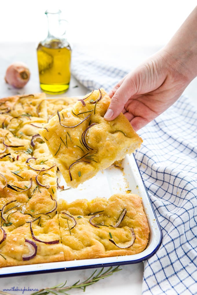 hand holding slice of rosemary onion focaccia bread