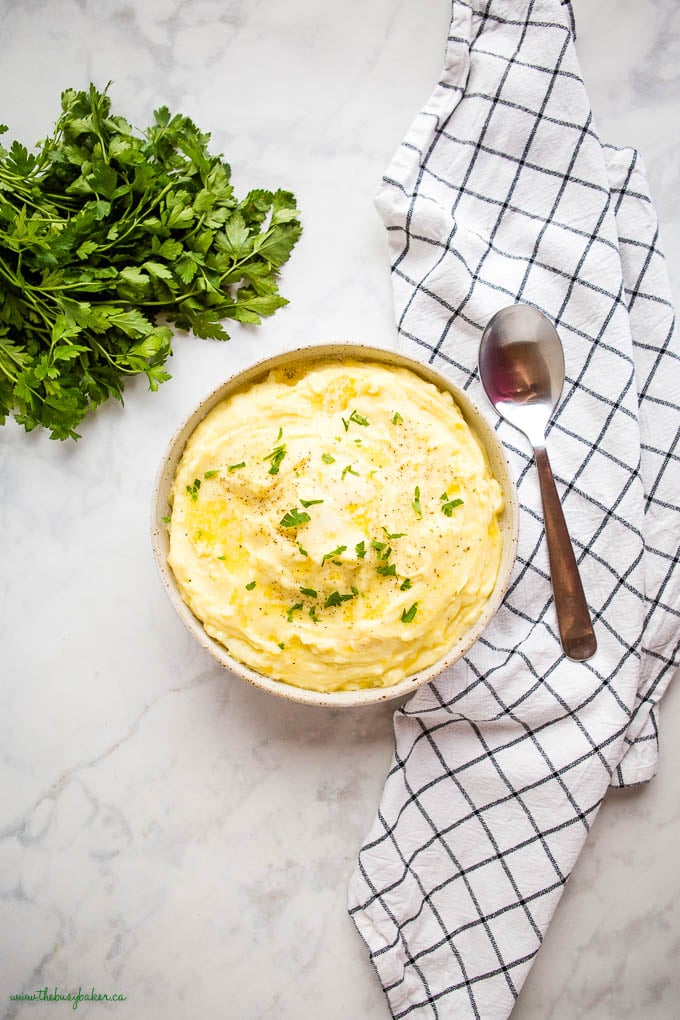 overhead image: bowl of mashed potatoes with melty butter and fresh chopped herbs