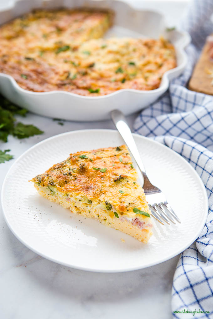 slice of crustless quiche on white plate with ham and broccoli