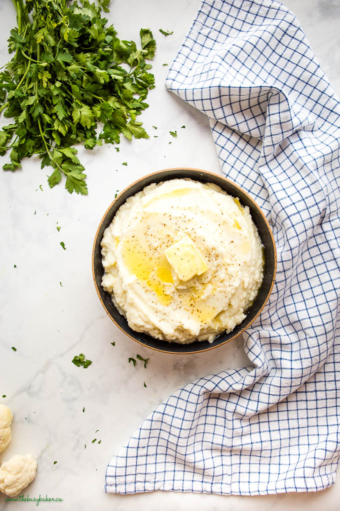overhead image: bowl of cauliflower mash with melted butter, salt and pepper