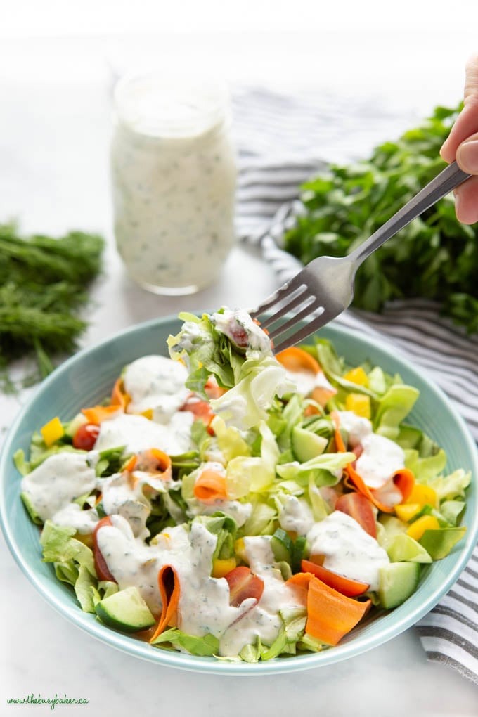 forkful of salad with ranch dressing in a blue bowl
