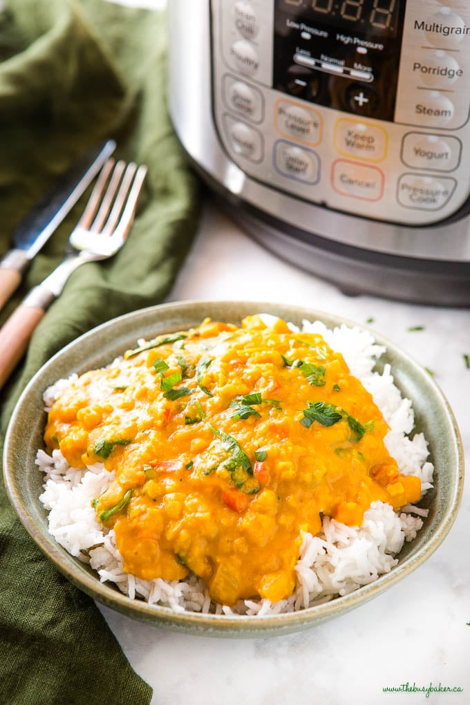 Lentil curry in a green bowl over rice with fresh herbs