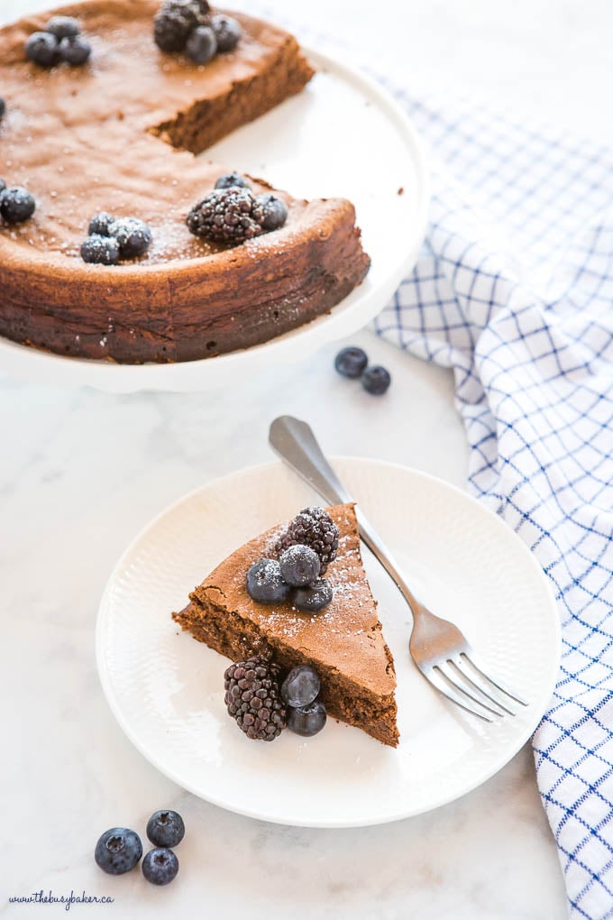 slice of keto flourless chocolate cake on white plate with berries