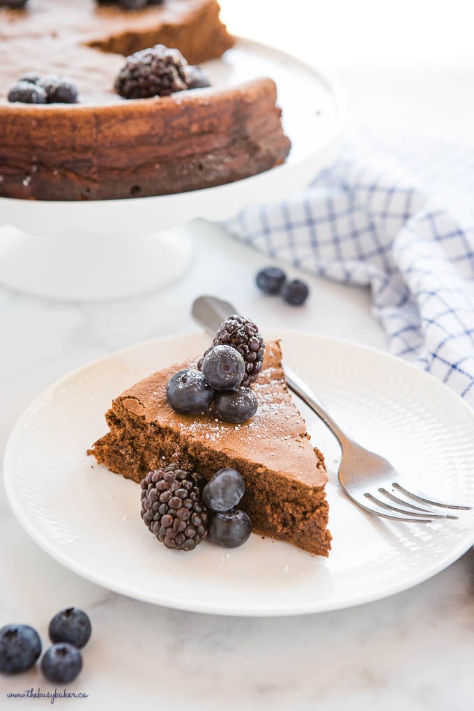 slice of keto flourless chocolate cake on white plate with berries