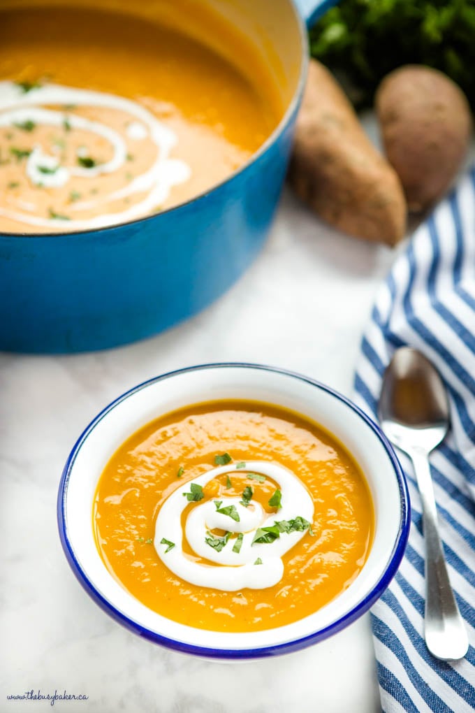 bowl of sweet potato soup with coconut cream and chopped herbs