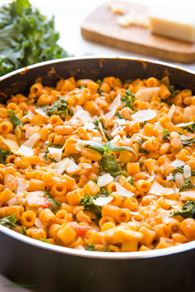 pasta with white beans in black pan with fresh basil