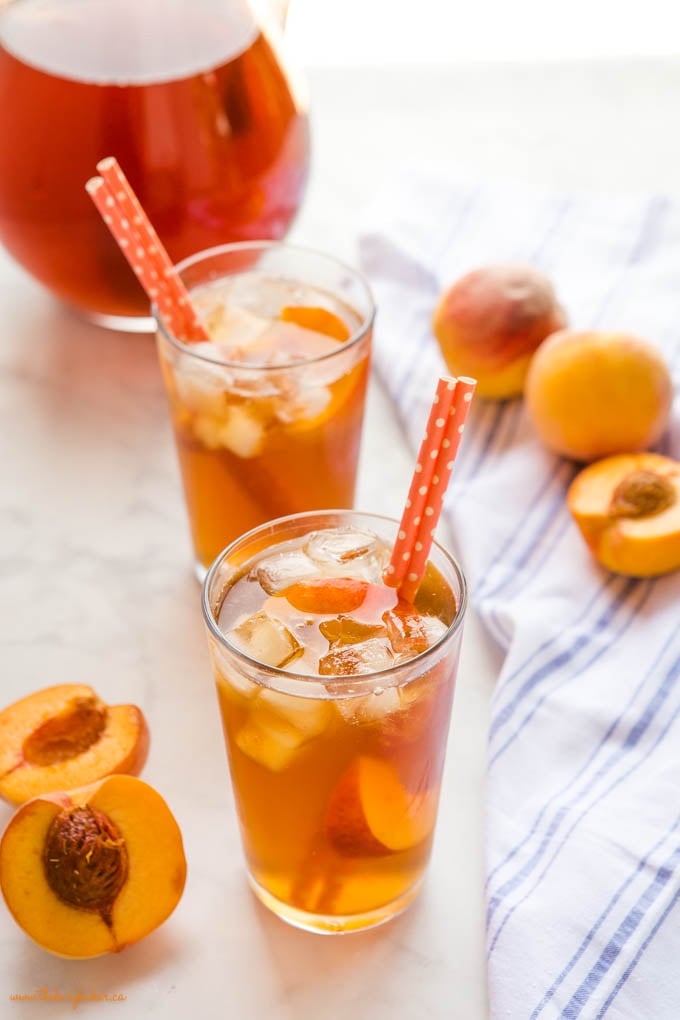 2 glasses of peach iced tea with ice and orange paper straws