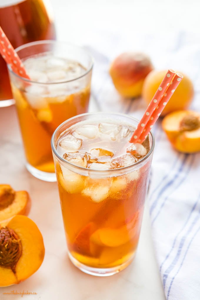 glass with peach iced tea and orange paper straws