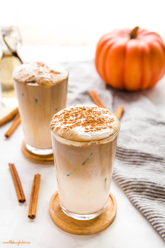 pumpkin spice iced latte with foam in tall glass with ice