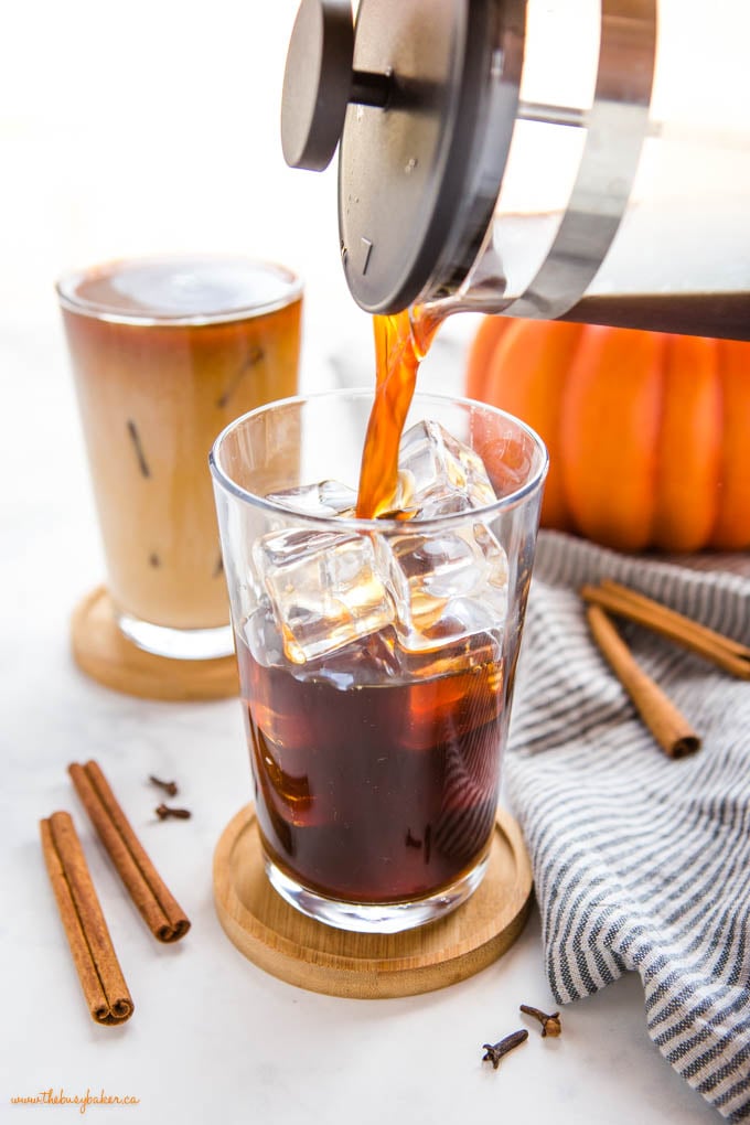 french press pouring cold brew coffee into a glass with ice