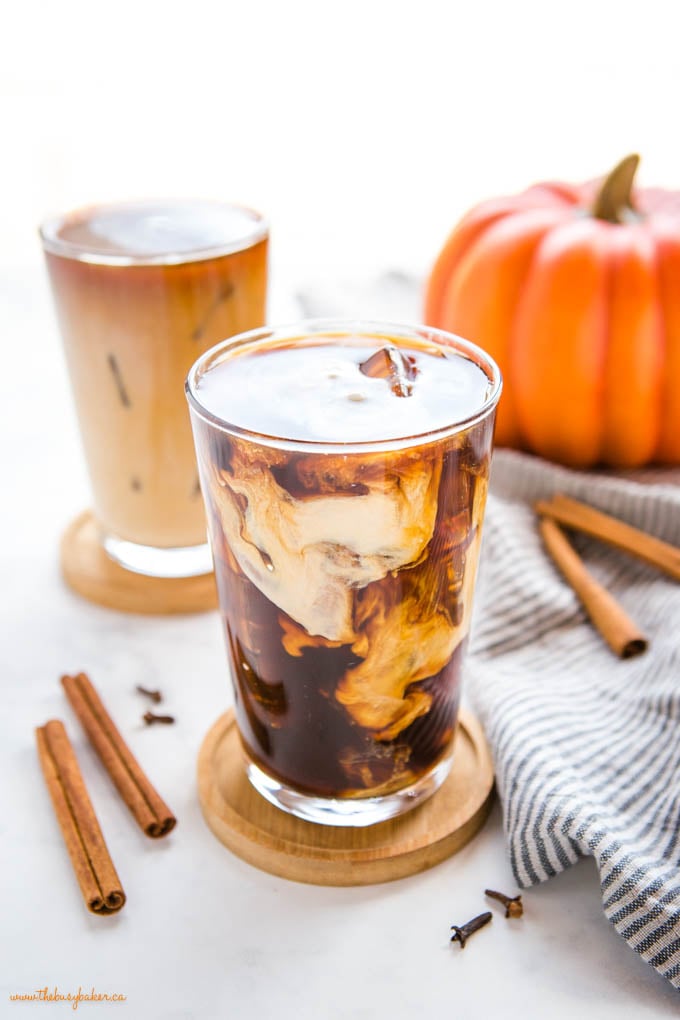 This Starbucks Pumpkin Cream Cold Brew is the perfect pumpkin spice iced coffee drink - easy-to-make cold brew coffee sweetened with a simple pumpkin cream made in a mason jar! Skip the coffee shop and make your favourite Pumpkin Cream Cold Brew at home! Recipe from thebusybaker.ca! #pumpkincreamcoldbrew #pumpkinspicelatte #pumpkinspice #pumpkin #fall #easytomake #coffee #homemade #starbucks #copycat starbucks pumpkin cream cold brew coffee in tall glass with ice