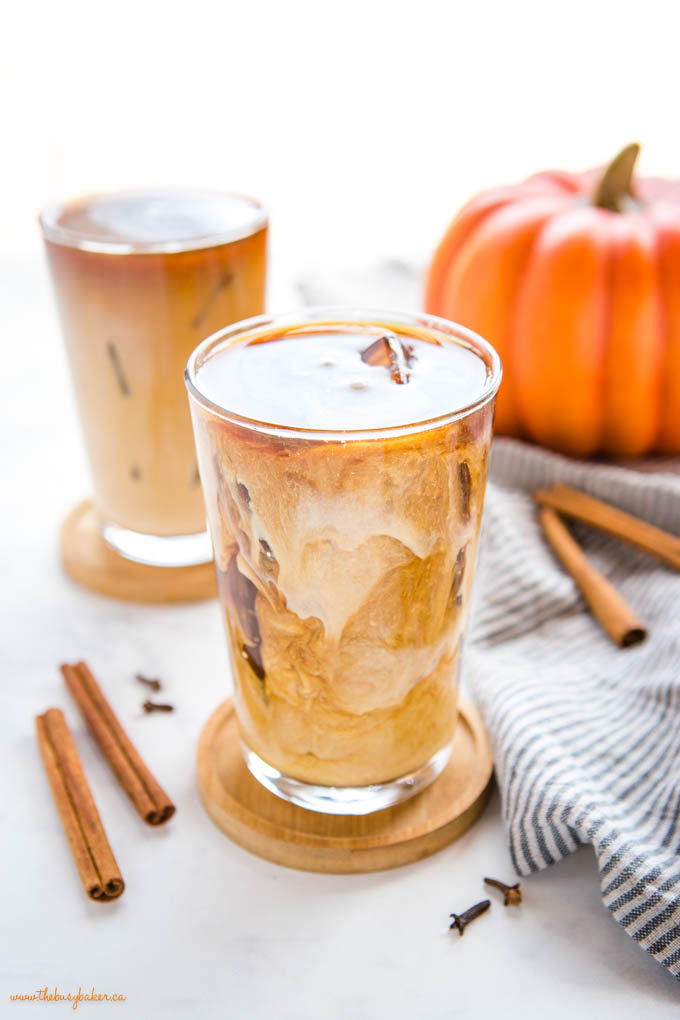 This Starbucks Pumpkin Cream Cold Brew is the perfect pumpkin spice iced coffee drink - easy-to-make cold brew coffee sweetened with a simple pumpkin cream made in a mason jar! Skip the coffee shop and make your favourite Pumpkin Cream Cold Brew at home! Recipe from thebusybaker.ca! #pumpkincreamcoldbrew #pumpkinspicelatte #pumpkinspice #pumpkin #fall #easytomake #coffee #homemade #starbucks #copycat swirls of pumpkin cream in coffee