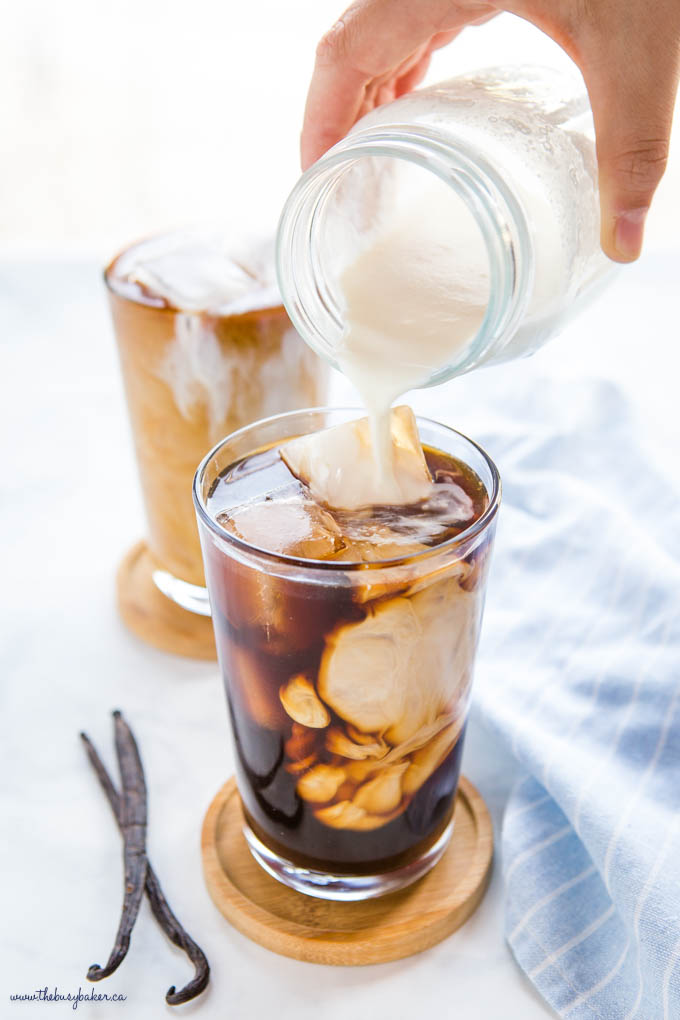 hand pouring sweet cream cold foam out of a mason jar into cold brew coffee