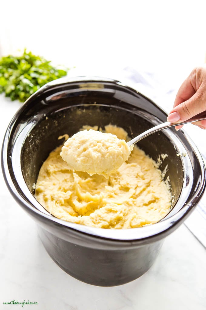 hand serving creamy mashed potatoes from crock pot