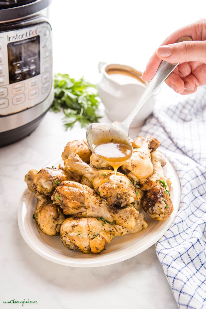 woman's hand spooning gravy over roast instant pot chicken drumsticks