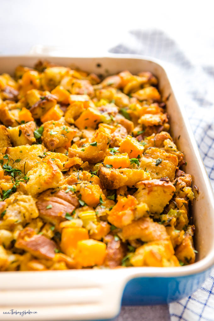 homemade stuffing with butternut squash and herbs in blue baking dish