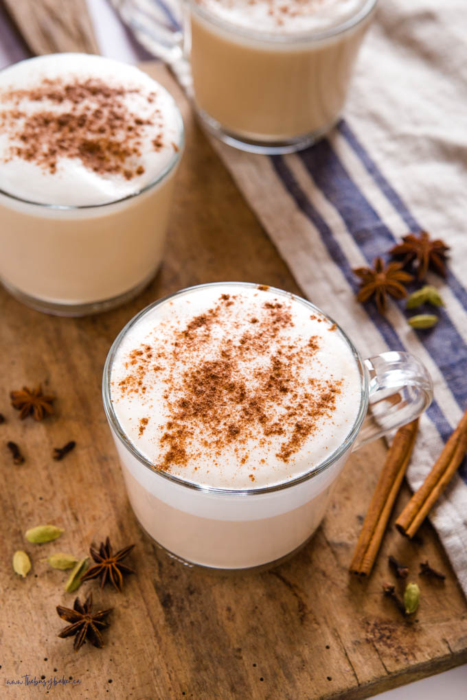 chai latte with foam and cinnamon in glass mug 