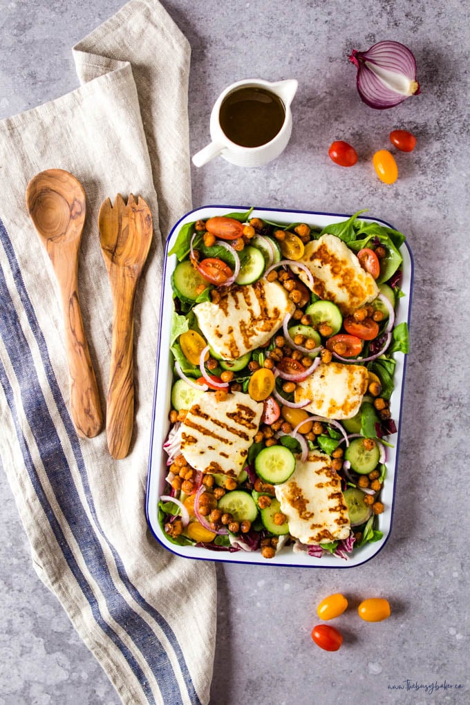 grilled halloumi salad with red onions, tomatoes, cucumbers, field greens, and crispy chickpeas