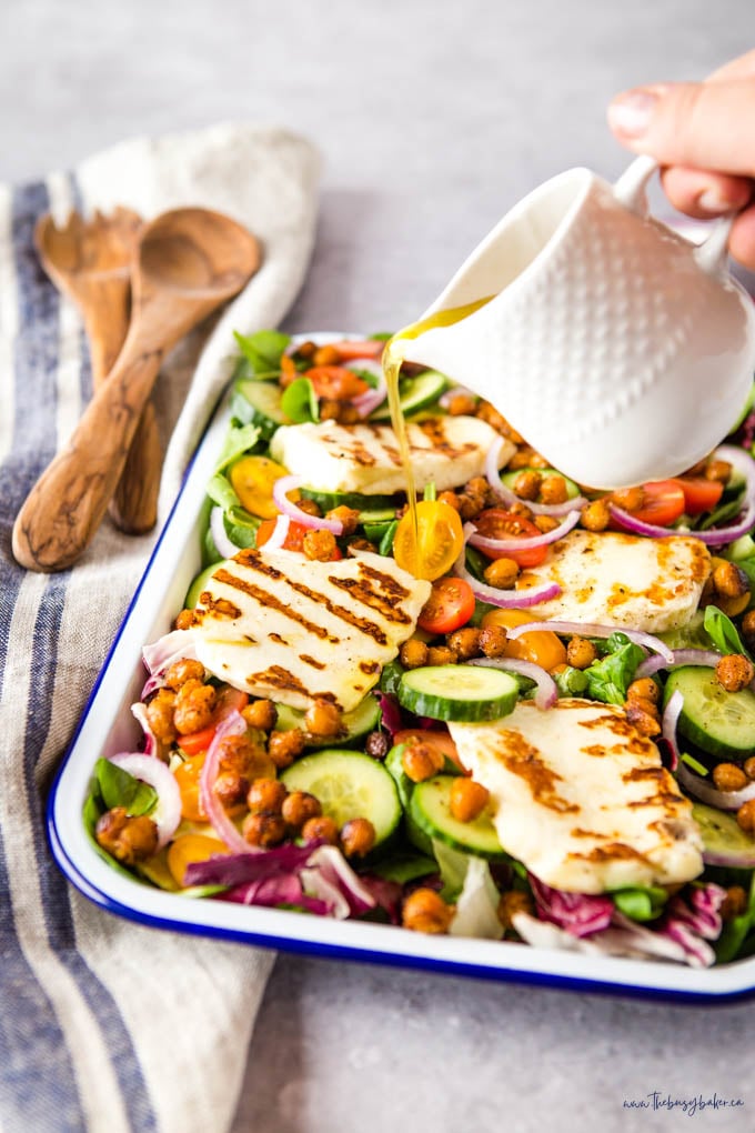 pouring dressing over grilled halloumi salad