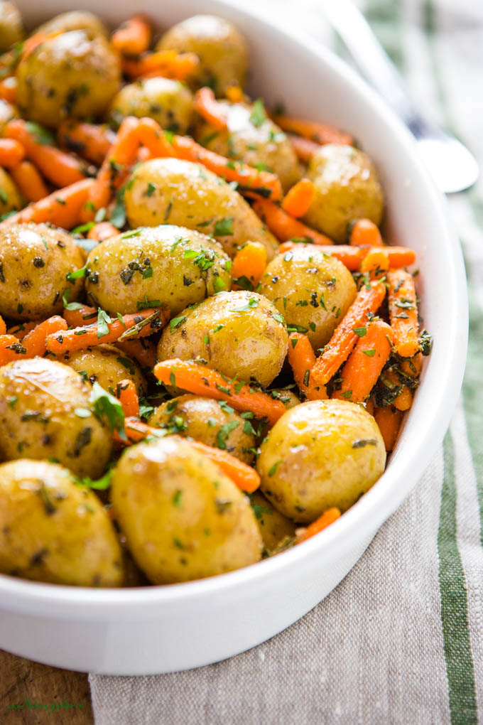 roasted potatoes and carrots in white serving dish