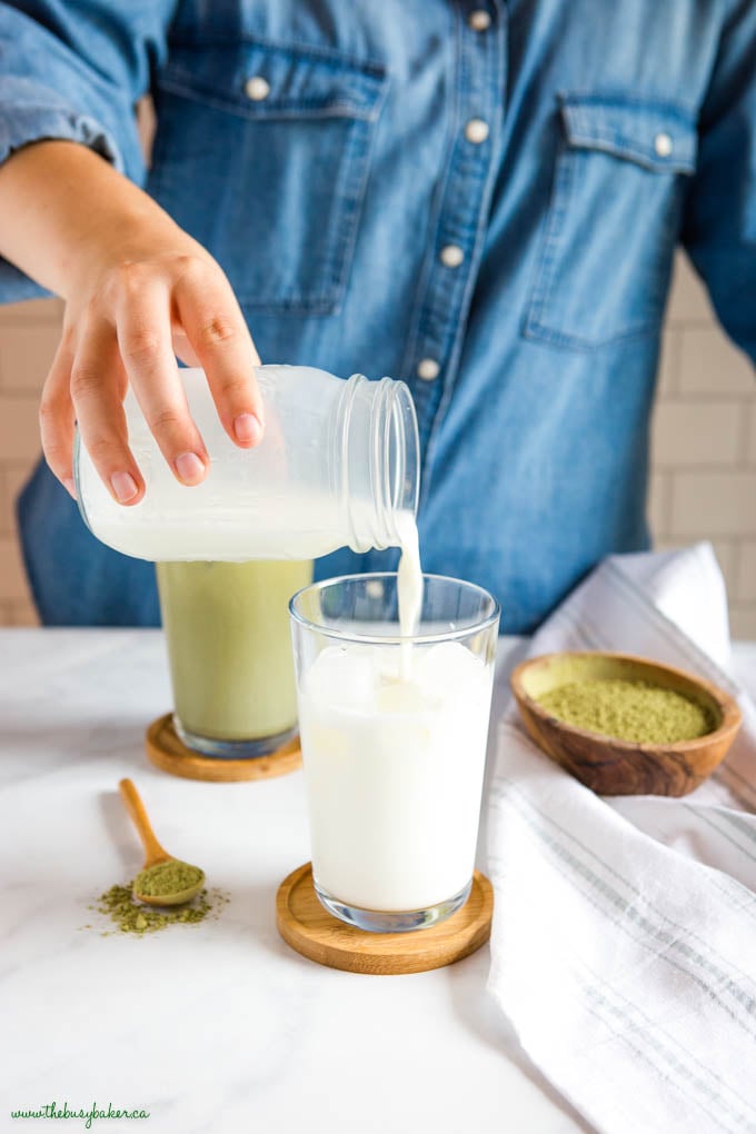 woman pouring foamed milk over ice in glass