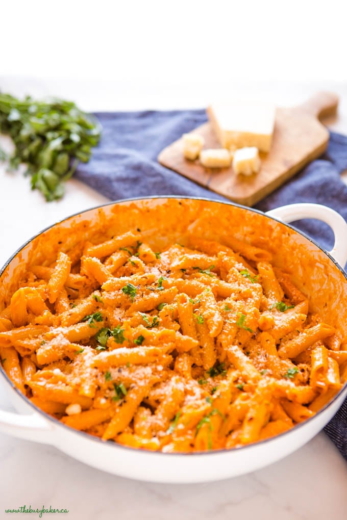 white enamel cast iron pan with pasta alla vodka and fresh herbs