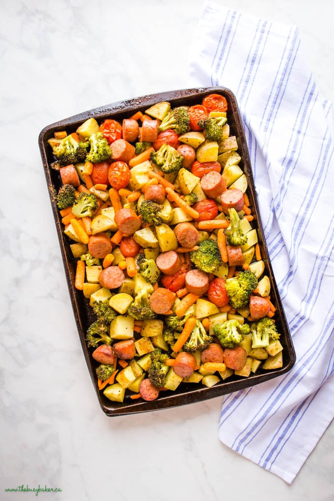 overhead image: black sheet pan with roasted potatoes, broccoli, sausages and carrots