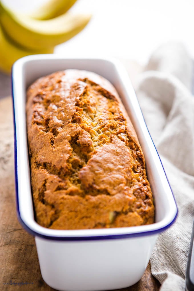 loaf of banana bread in white enamel tin with a blue rim