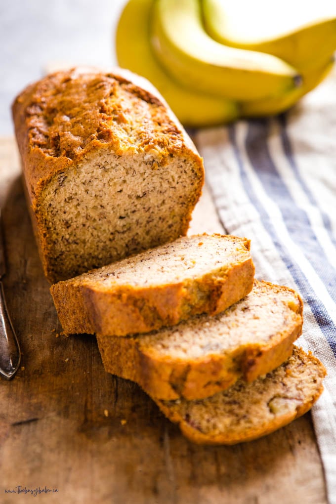 loaf of vegan banana bread sliced on wooden cutting board