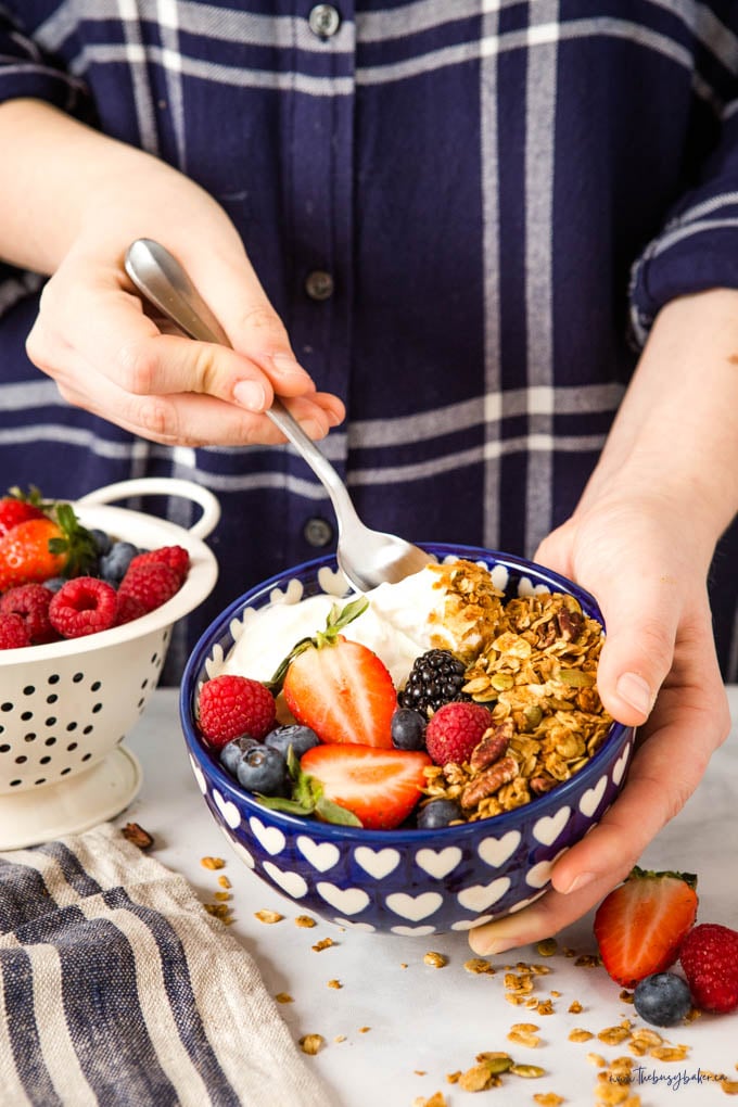 woman holding spoonful of yogurt and homemade granola