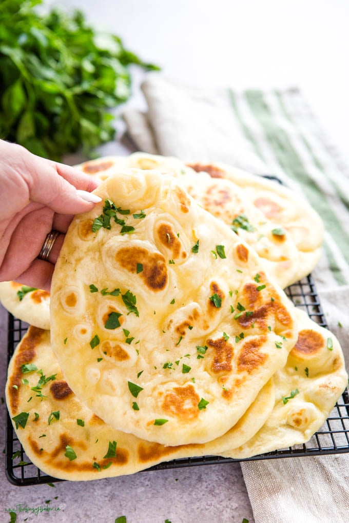 hand holding naan bread with fresh green herbs
