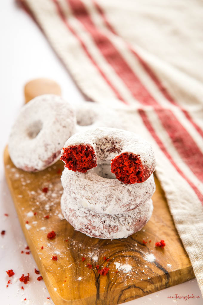 red velvet donuts in a stack with powdered sugar