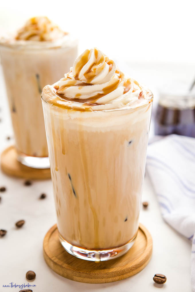 iced caramel latte in tall glass with whipped cream and caramel sauce