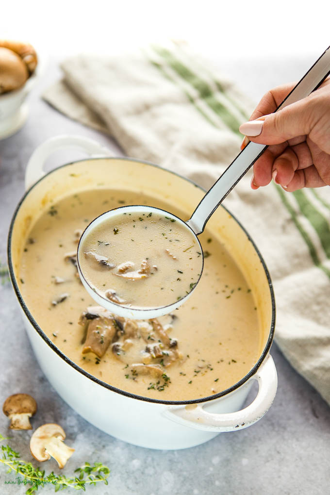 woman's hand serving creamy homemade mushroom soup