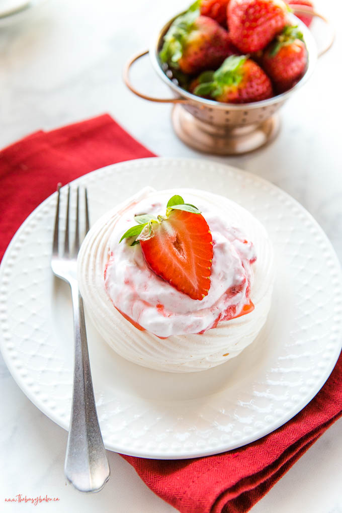 mini pavlova on white plate with strawberry and cream