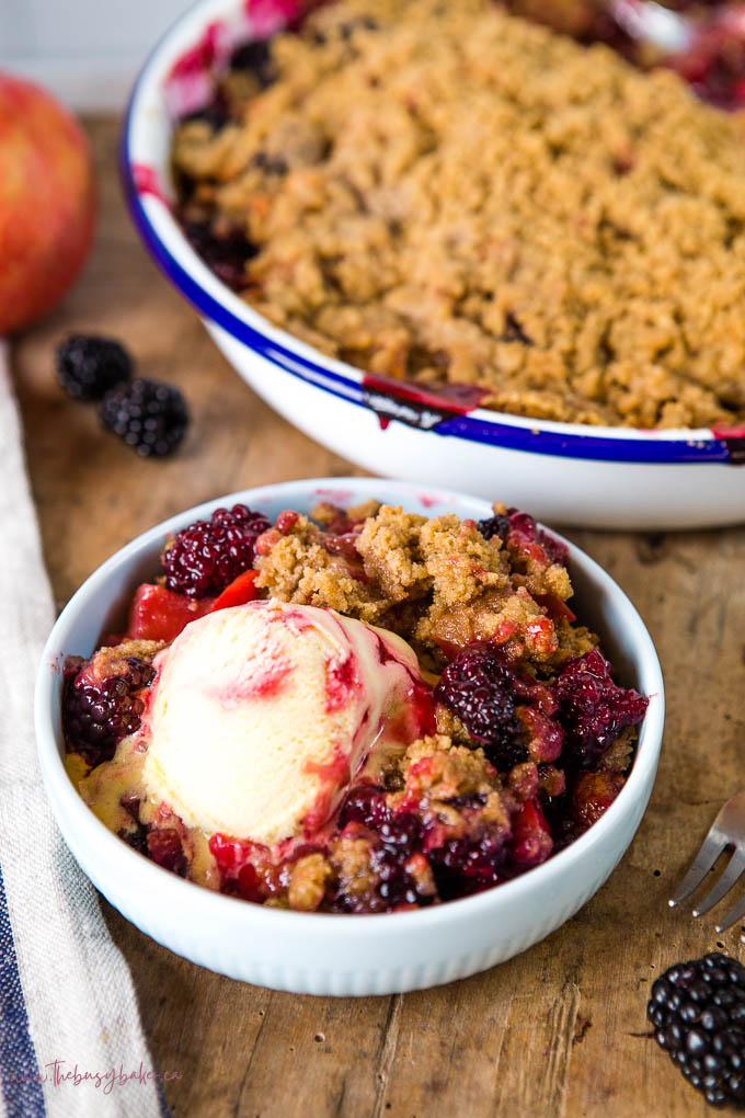 apple and blackberry crumble in blue bowl with ice cream