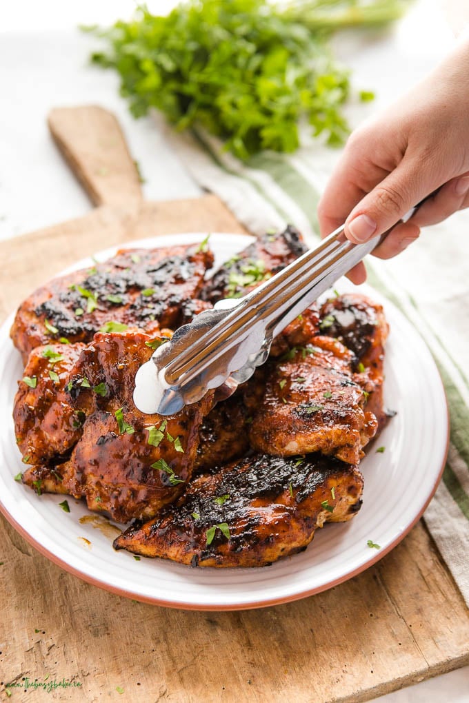 tongs placing a piece of chicken on the plate