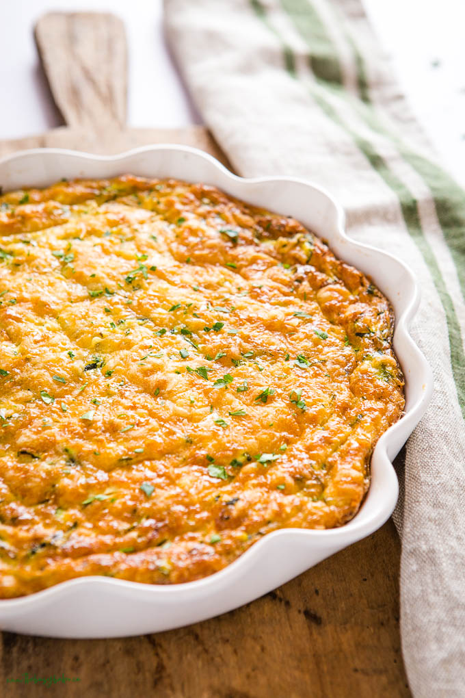 This Zucchini Slice recipe is part quiche & part pie, and it's packed with veggies, cheese, & savoury flavours! The perfect breakfast or lunch! Recipe from thebusybaker.ca! #zucchinislice #zucchini #quiche #eggs #brunch #pie #breakfast zucchini quiche pie recipe