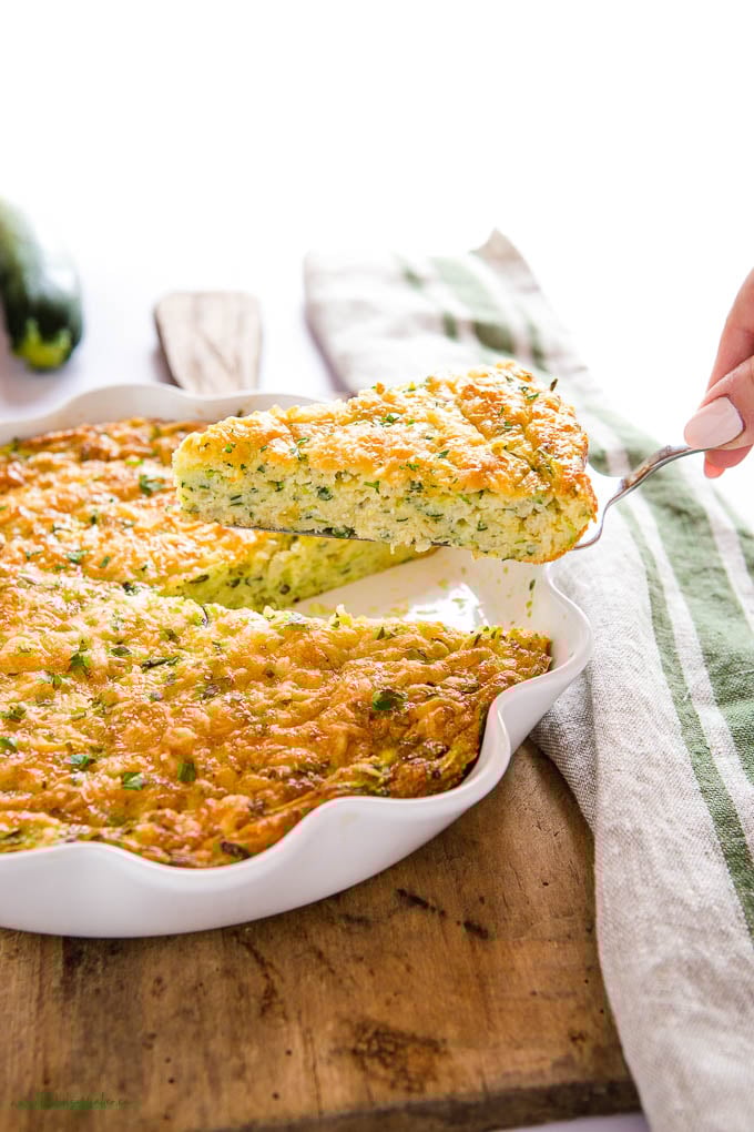 This Zucchini Slice recipe is part quiche & part pie, and it's packed with veggies, cheese, & savoury flavours! The perfect breakfast or lunch! Recipe from thebusybaker.ca! #zucchinislice #zucchini #quiche #eggs #brunch #pie #breakfast zucchini slice on pie lifter