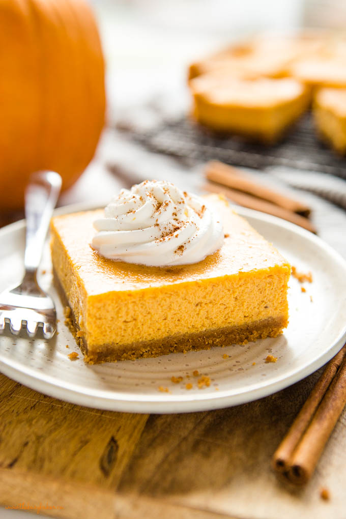 square pumpkin cheesecake bar with whipped cream and cinnamon on top