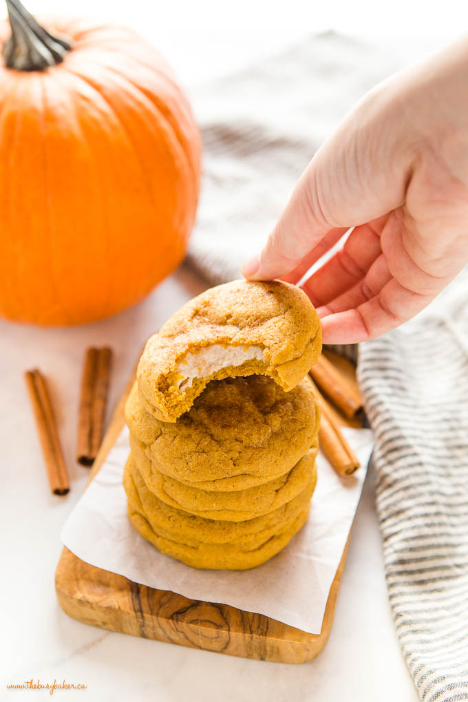 hand reaching for half-eaten pumpkin cheesecake cookie